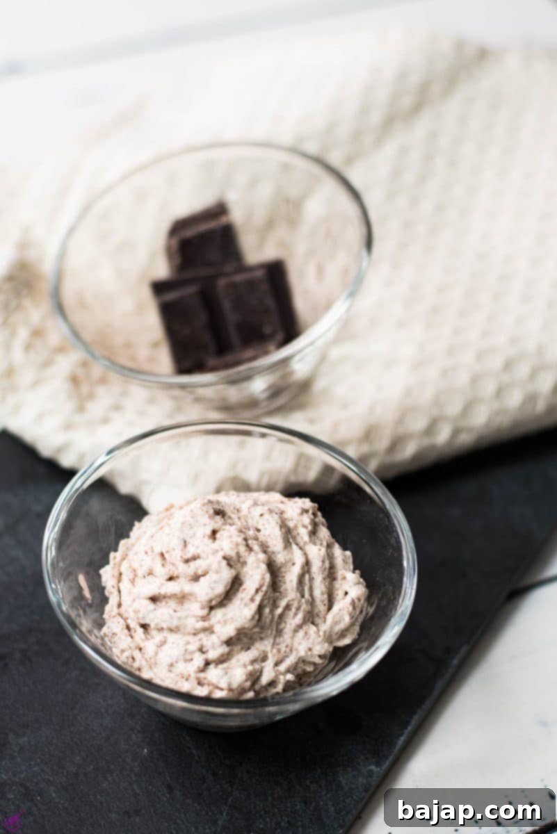 Two glass cups, one filled with delicious chocolate flavored whipped cream, the other with two small chocolate bars.