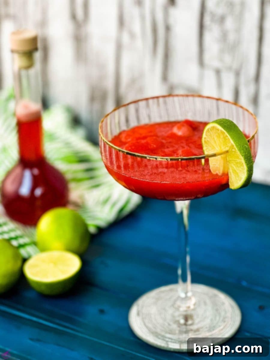 Gorgeous cocktail glass, with golden rim, filled with frozen strawberry daiquiri, perfect for summer.