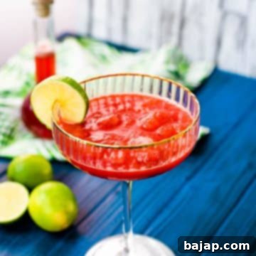 Gorgeous cocktail glass, with golden rim, filled with frozen strawberry daiquiri.