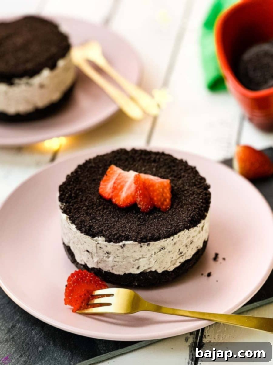 Mini no-bake Oreo cheesecake on a pink plate decorated with sliced strawberries.