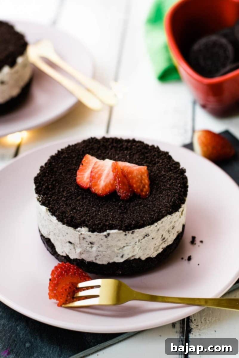 Mini no-bake Oreo cheesecake on a pink plate decorated with sliced strawberries.