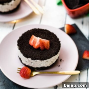 Mini no-bake Oreo cheesecake on a pink plate decorated with sliced strawberries.