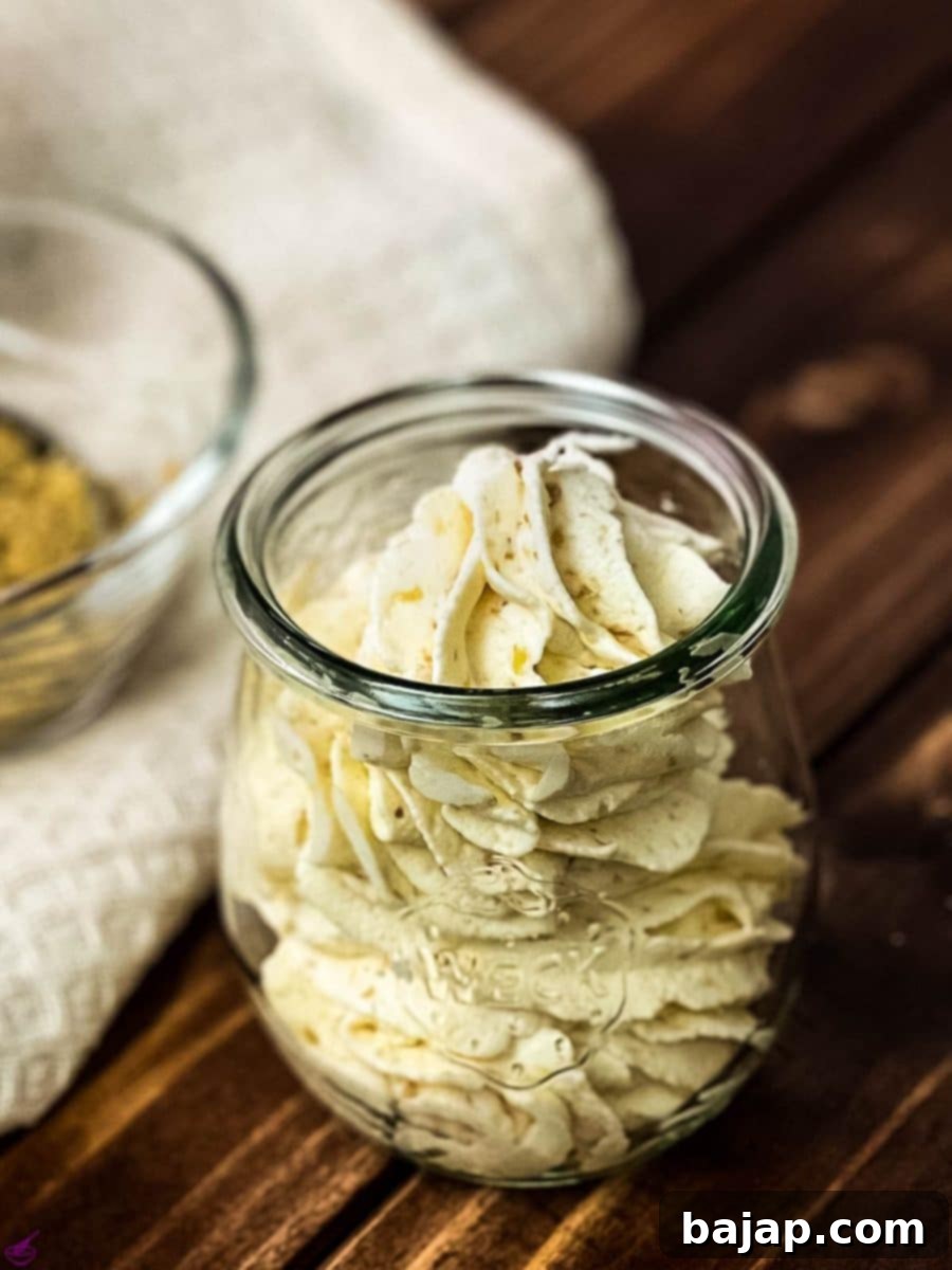 Lush almond whipped cream delicately piped into a elegant Weck jar, resting on a rustic wooden surface, highlighting its creamy texture and artisanal presentation.