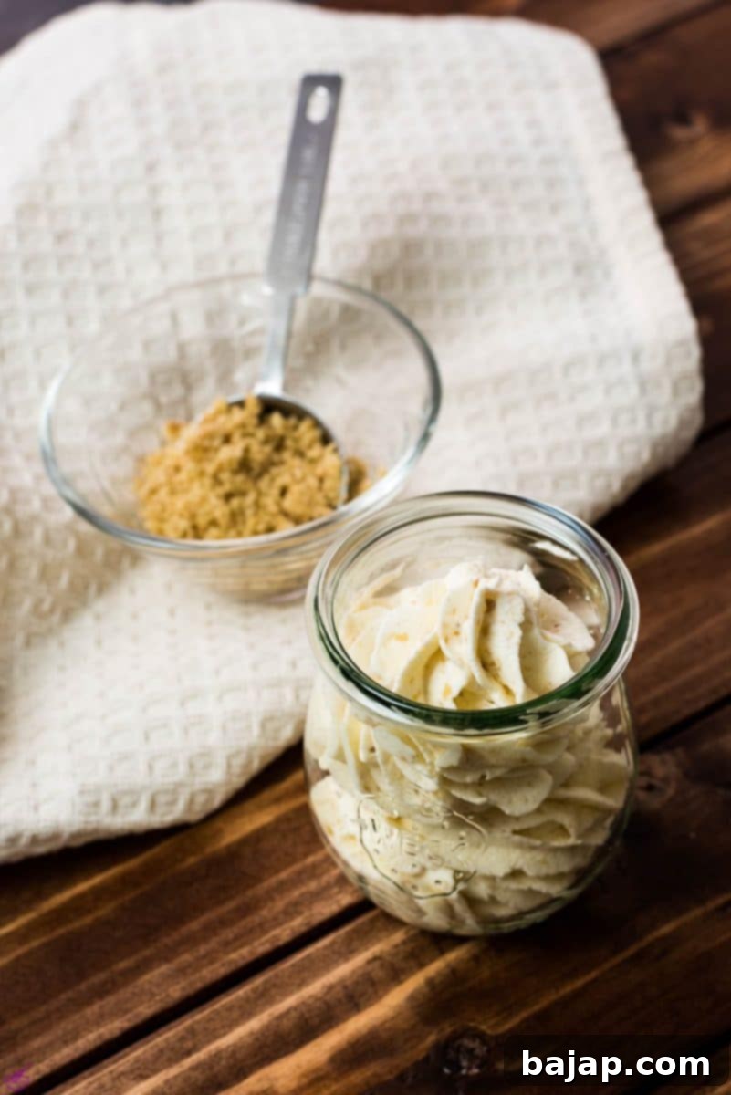 Freshly piped almond whipped cream beautifully presented in a Weck Jar, set against a warm wooden backdrop, ready to be savored.