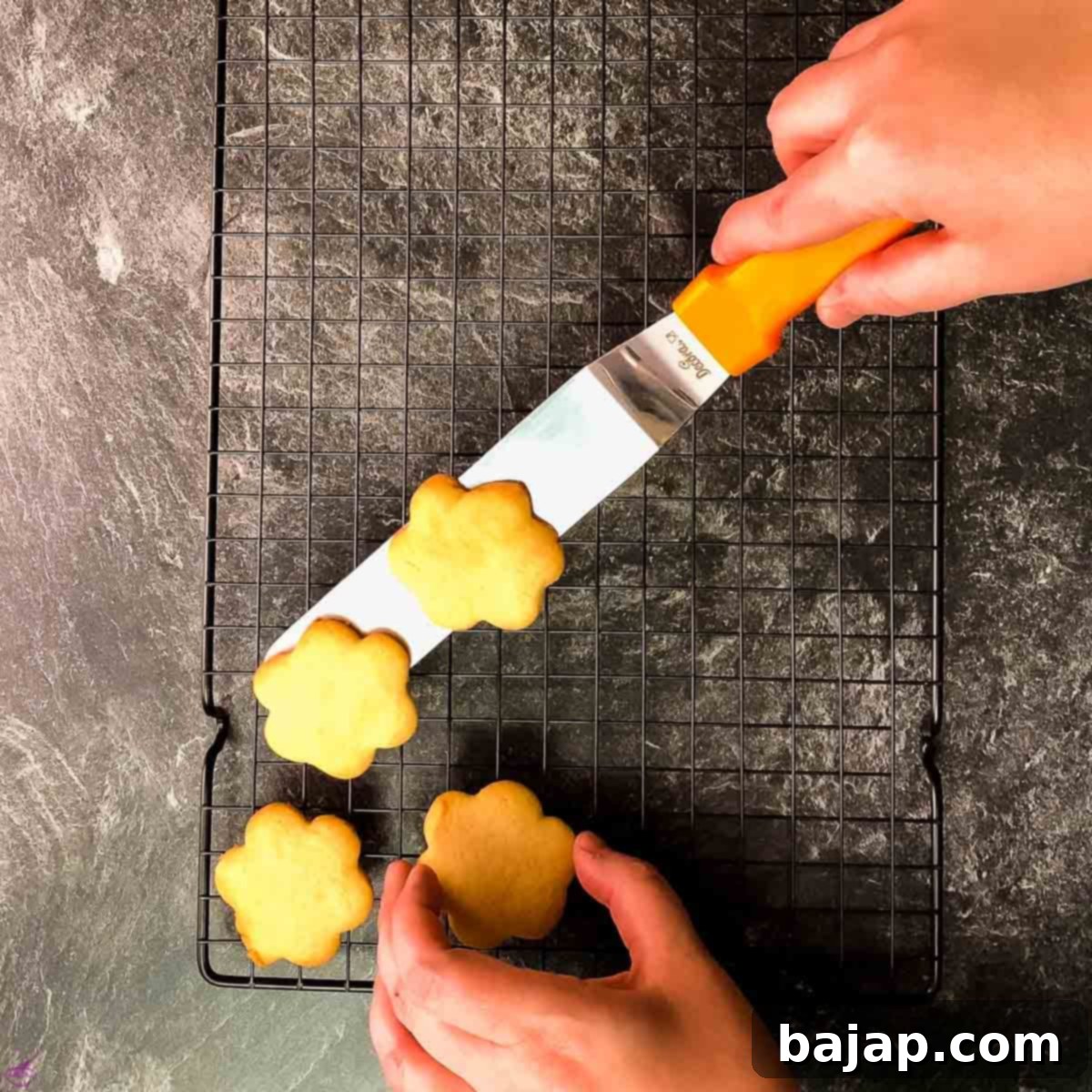 Flower shape sugar cookies on cooling rack.