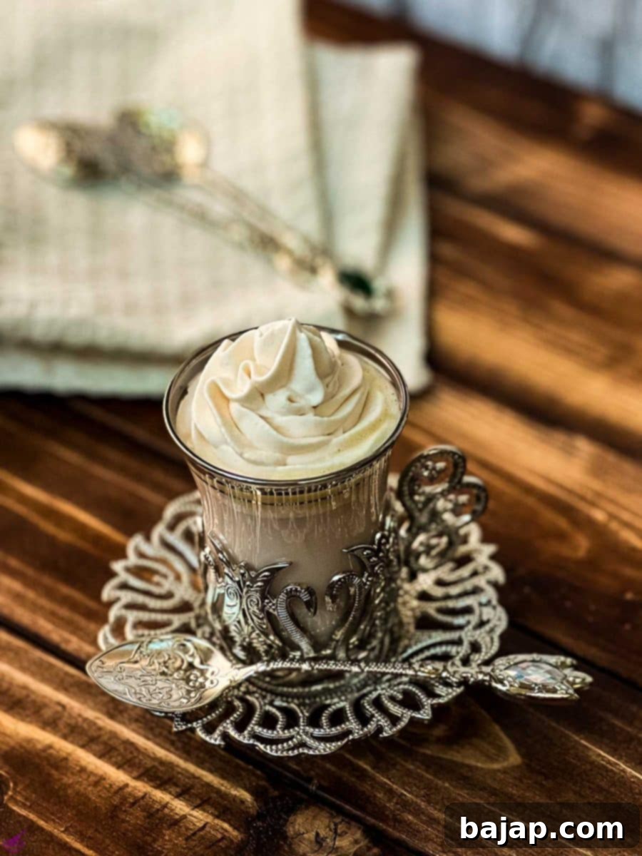 A gorgeous glass filled with strawberry hot chocolate and topped with a rosette of strawberry flavored whipped cream.