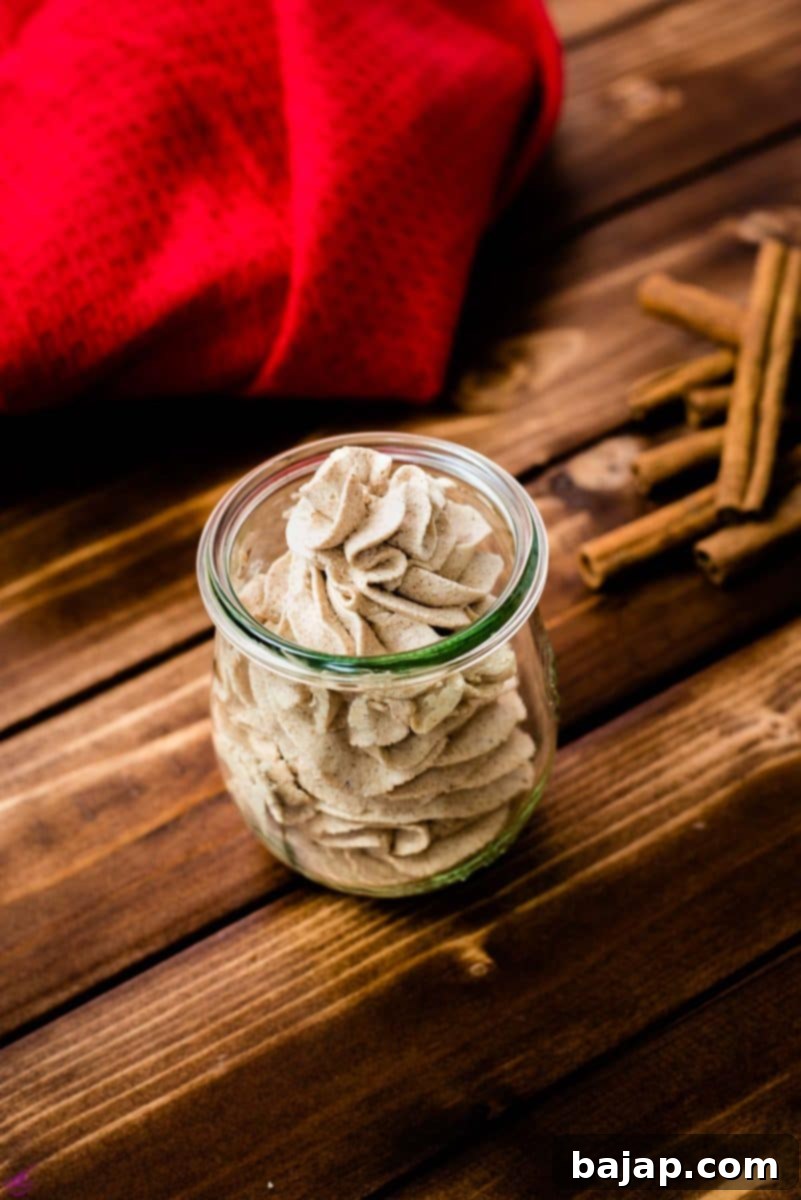Gorgeous cinnamon whipped cream, in tulip formed Weck glass on a wooden floor.
