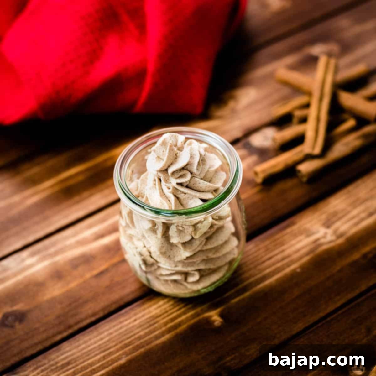 Gorgeous cinnamon whipped cream, in tulip formed Weck glass on a wooden floor.