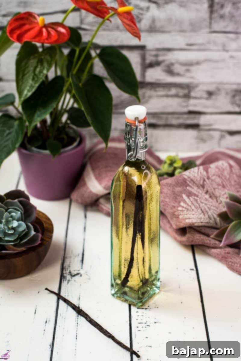A beautiful bottle with amber-colored homemade vanilla vodka on a white wooden base.