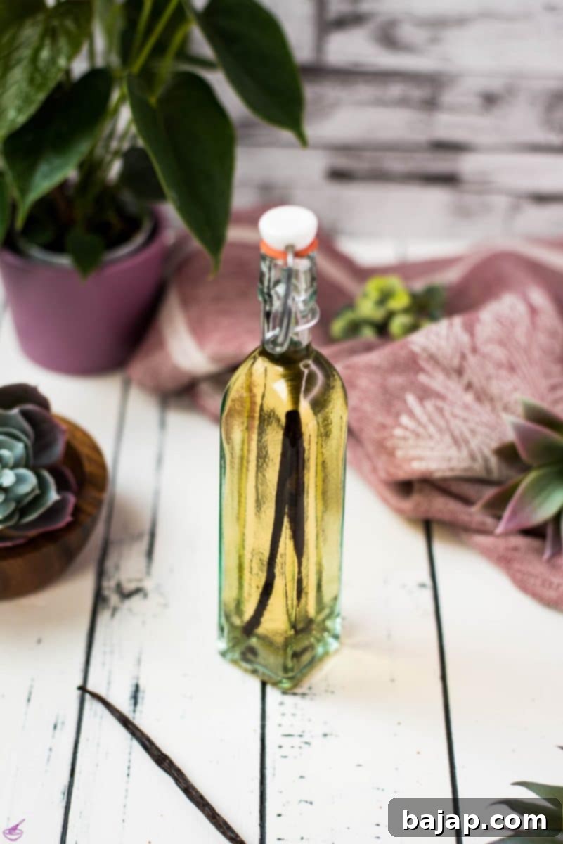 A beautiful bottle with amber-colored homemade vanilla vodka on a white wooden base.