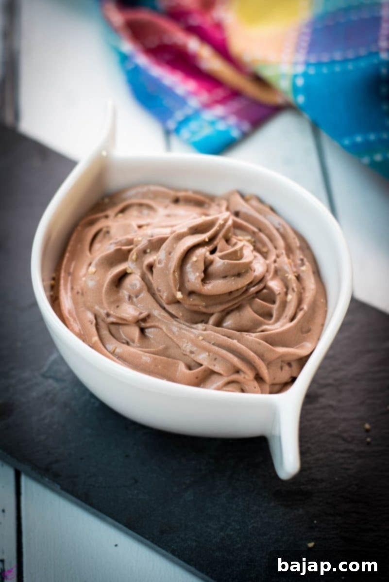 A pristine white ceramic bowl brimming with luscious, dark chocolate pudding, artfully presented on a sleek black slate plate, garnished with fresh berries and a hint of cocoa powder.