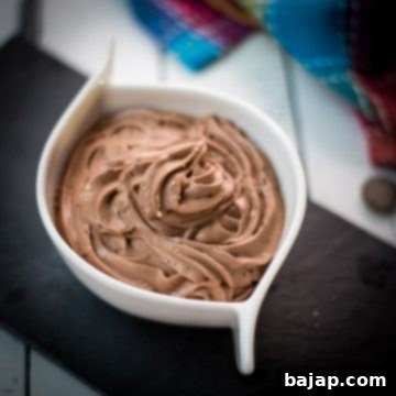 White ceramic bowl filled with delicious dark chocolate pudding on black slate plate.