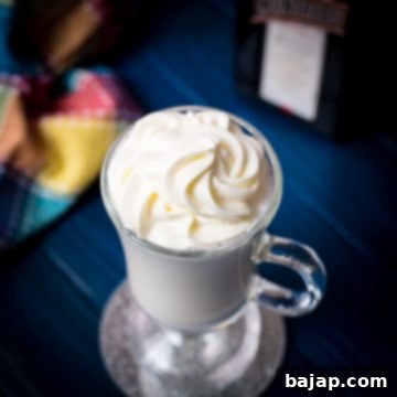 Delicious white Cointreau (orange liqueur) milkshake for adults on mirror glass coaster and dark blue wooden base.