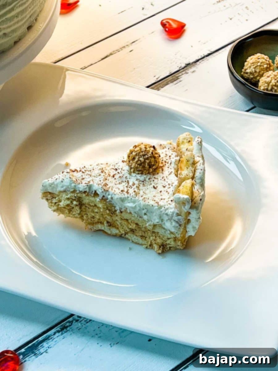 A beautiful slice of a delicious almond cream cake. Garnished with whipped cream, grated chocolate and a Giotto. Served on white plate on white wooden background.