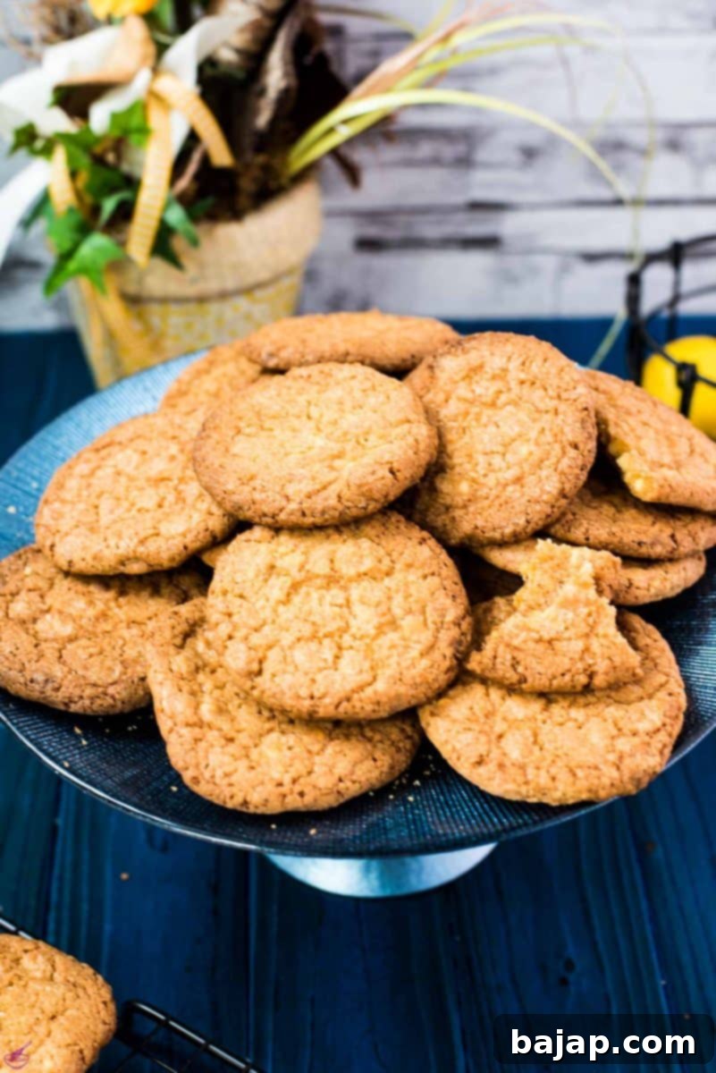 Close-up of freshly baked lemon white chocolate chip cookies on a blue cake stand, highlighting their golden-brown edges and melted white chocolate chips.