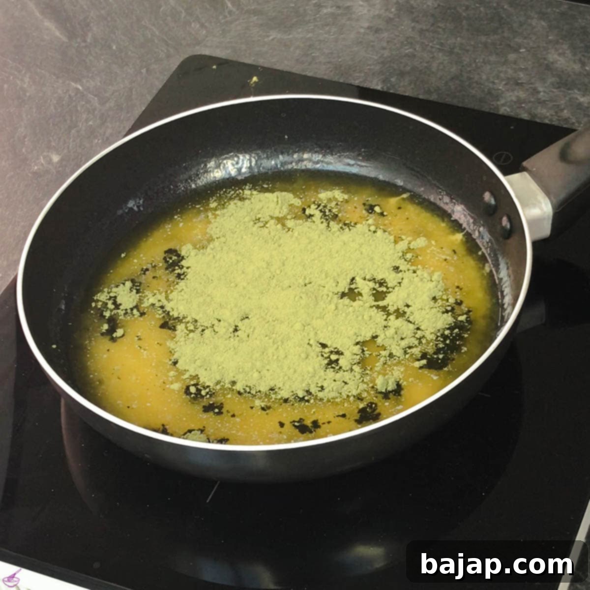Effortless Matcha Butter Recipe 5 Matcha powder being carefully added to the freshly melted butter in a small frying pan, prior to whisking.