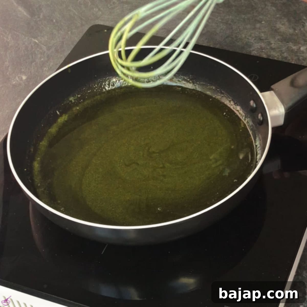 Effortless Matcha Butter Recipe 6 Close-up shot of the melted butter and matcha powder being vigorously whisked together in a pan to create a smooth, lump-free mixture.