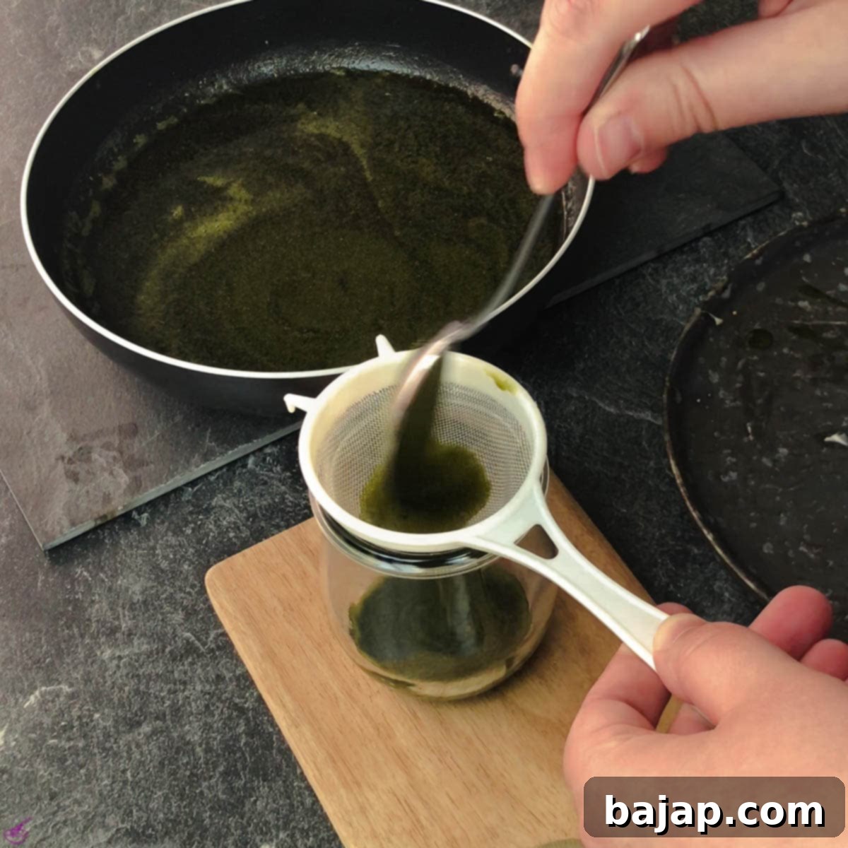 Effortless Matcha Butter Recipe 7 The vibrant green matcha-infused butter being sieved through a close-meshed sieve into a clean glass jar, ensuring a perfectly smooth consistency.