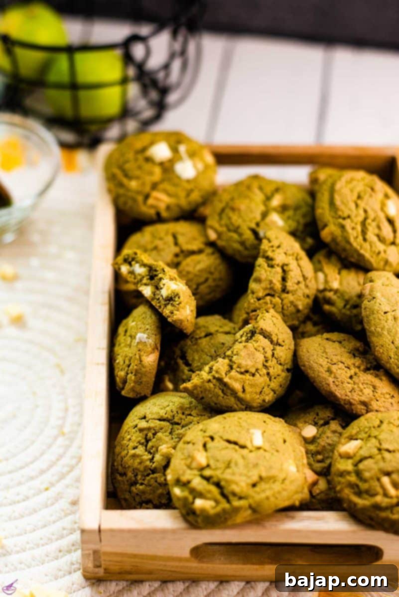 Delicious white chocolate chip matcha cookies with a hint of lime flavor - chewy and soft at the same time. Placed on a wooden tray.