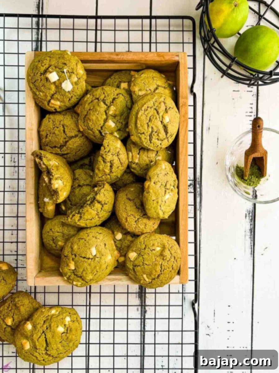 Delicious white chocolate chip matcha cookies with a hint of lime flavor - chewy and soft at the same time. Placed on a wooden tray and cooling rack.