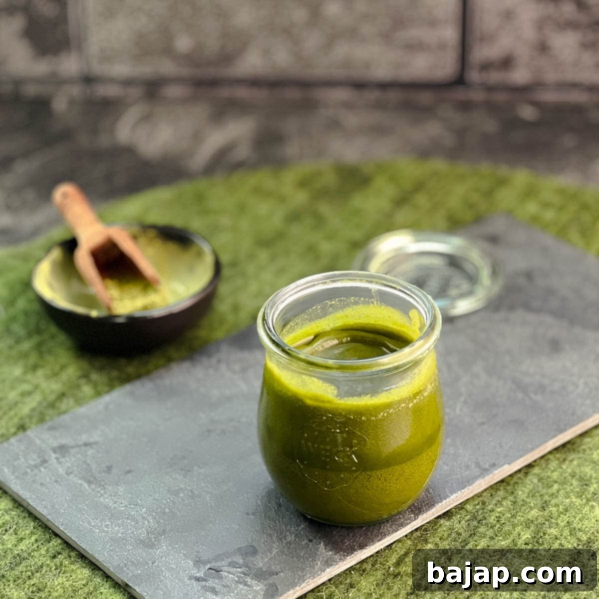 A preserving jar filled with Matcha butter after cooling, placed on a slate plate, ready for baking.