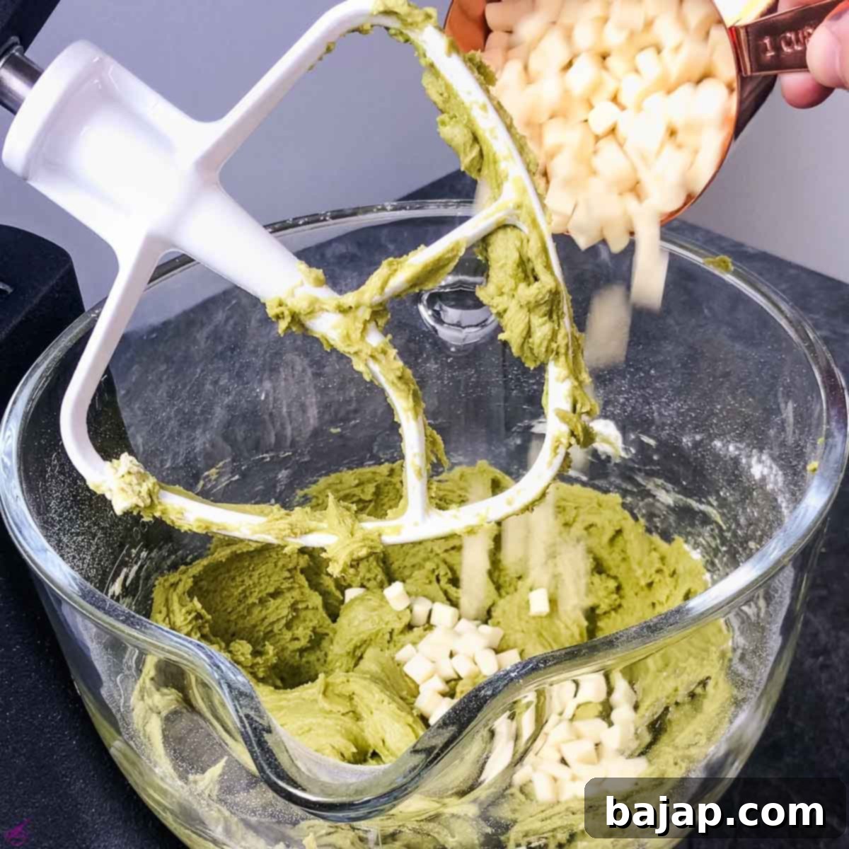 Add the white chocolate chips to the vibrant Matcha cookie batter.
