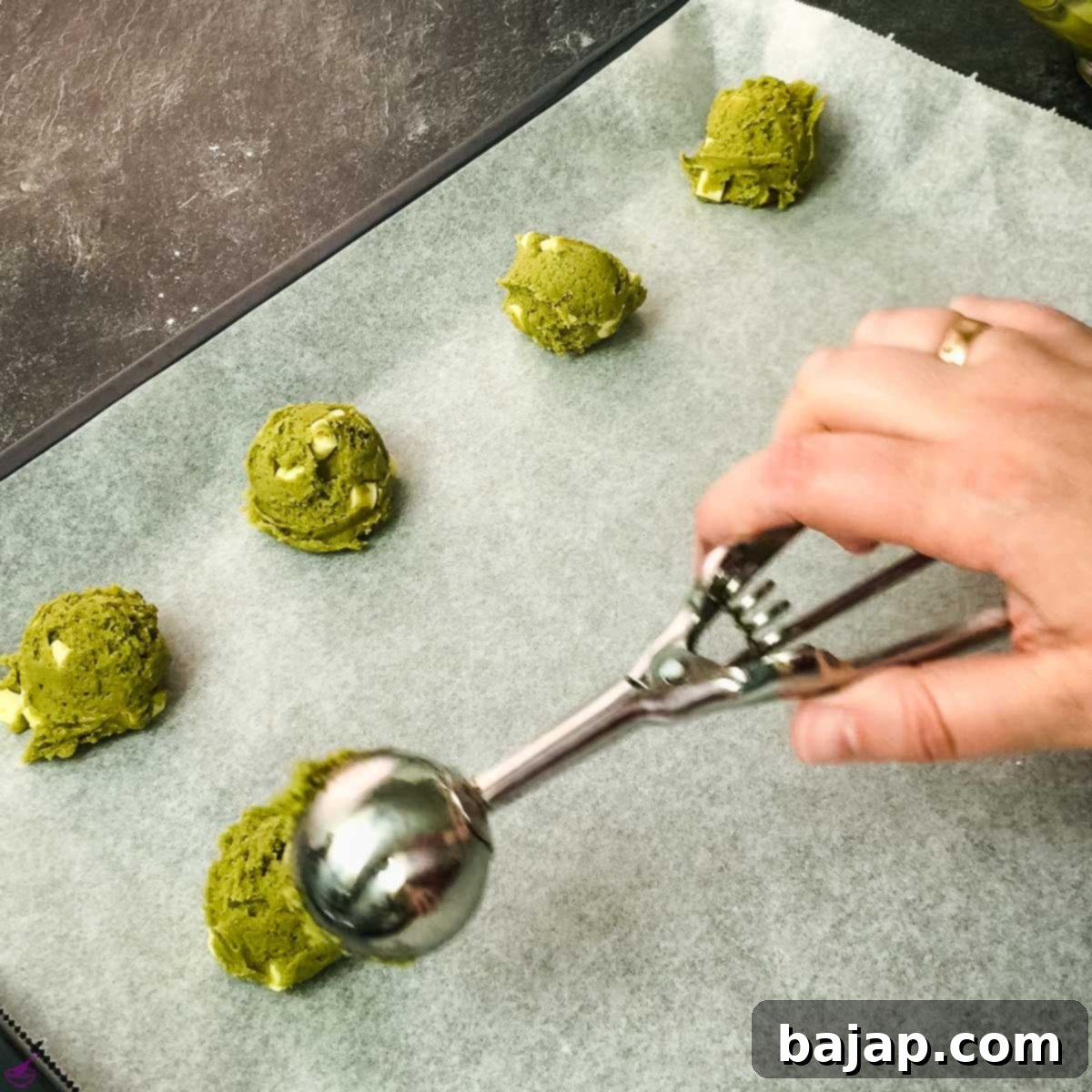Scooped Matcha cookie dough balls, perfectly portioned on a baking sheet before baking.