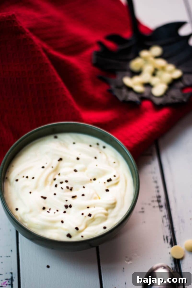 A gorgeous green bowl filled with delicious white chocolate pudding sits on a rustic white wooden board, ready to be enjoyed.