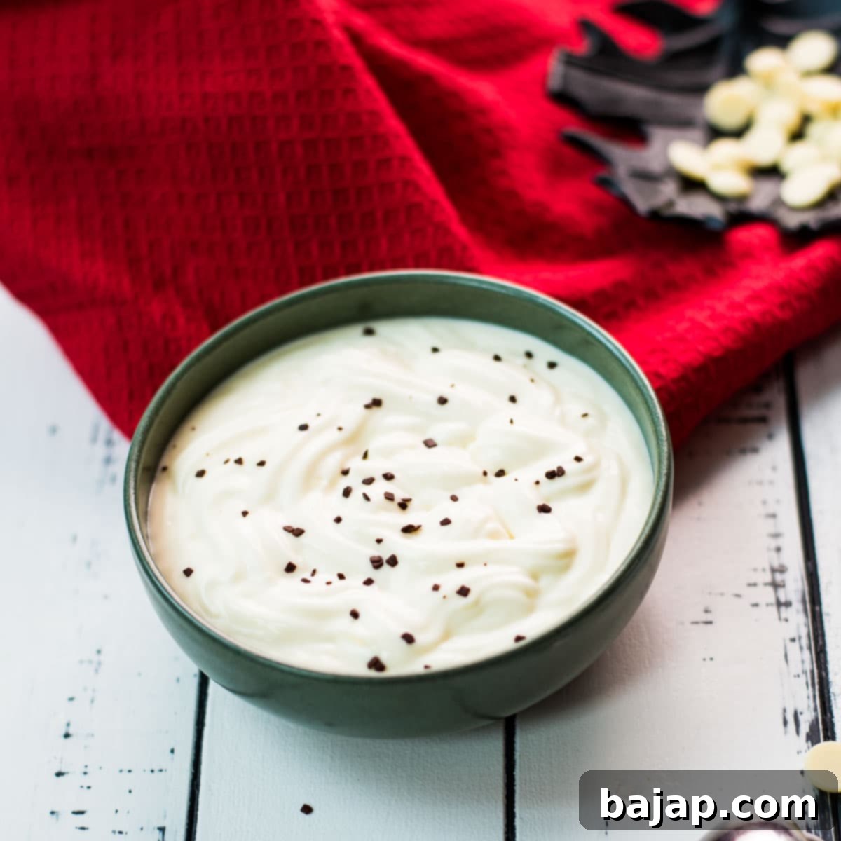 Gorgeous green bowl on white wooden board filled with delicious white chocolate pudding.