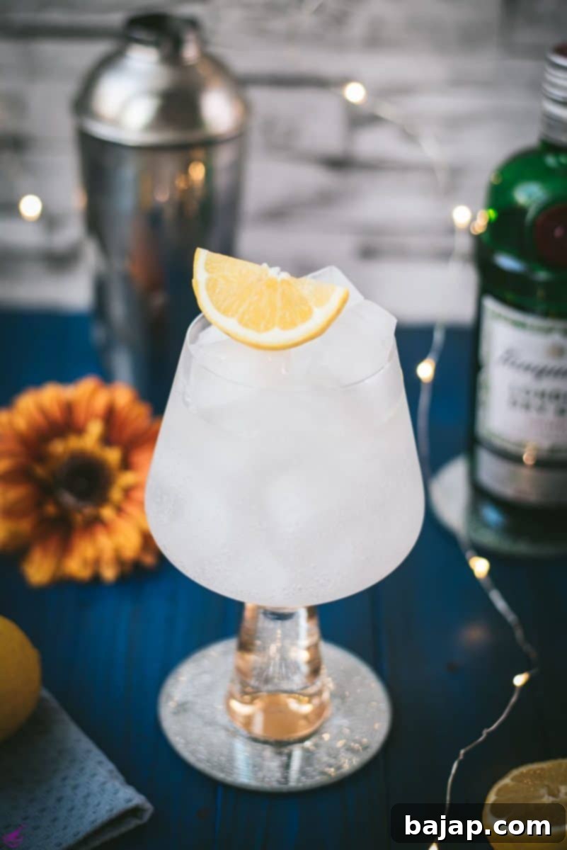 Gorgeous glass filled with a refreshing lemon gin and tonic. Placed on blue wooden ground.