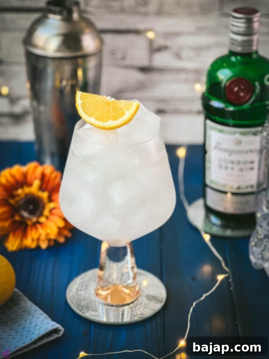 Gorgeous glass filled with a refreshing lemon gin and tonic. Placed on blue wooden ground.