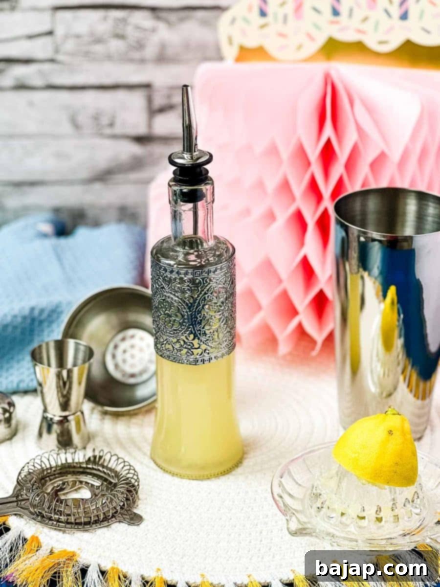 Bottle filled with freshly squeezed lemon juice fitted with a pouring spout, surrounded by cocktail making tools.