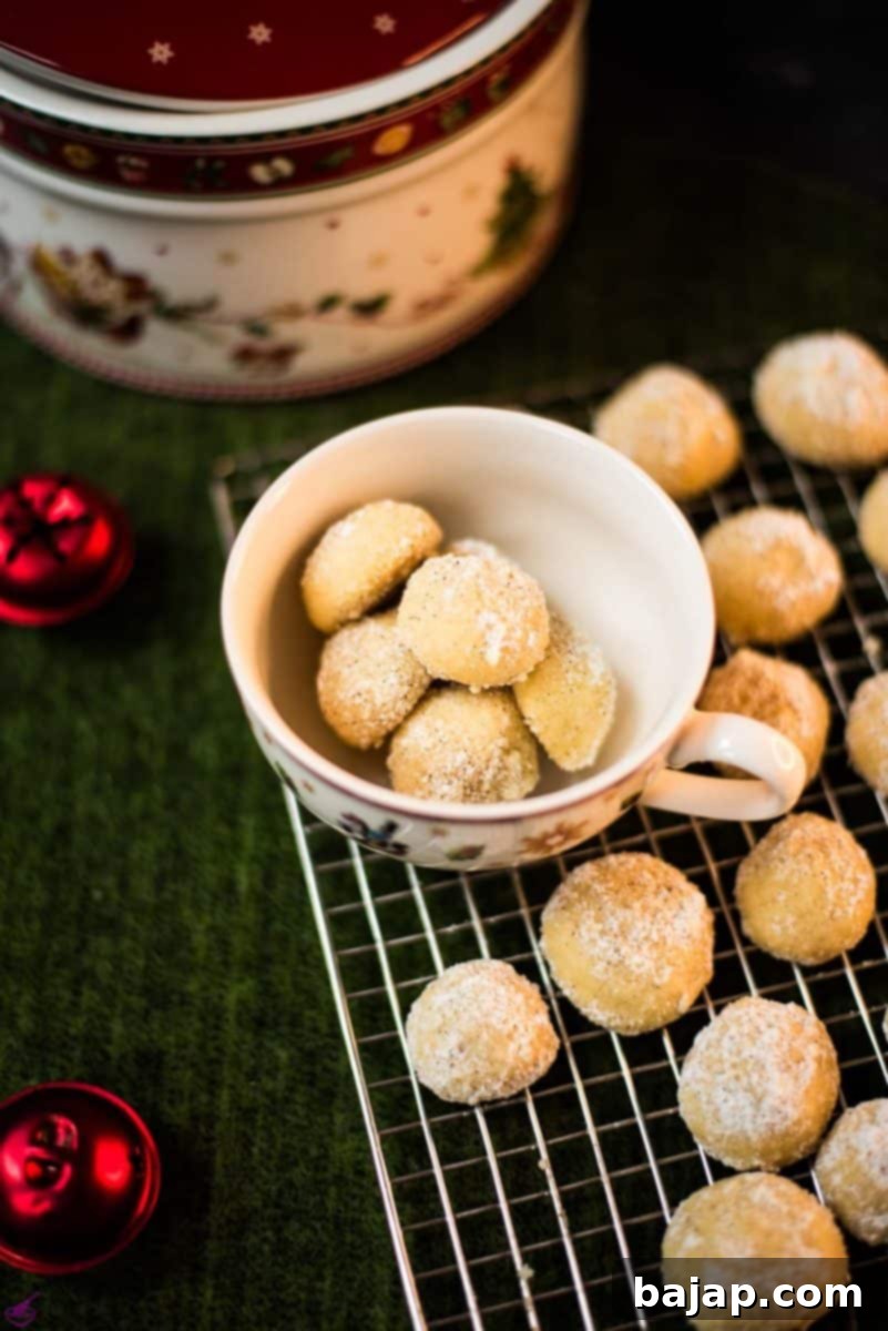 Melt-in-your-mouth butterball cookies on placed on cooling rack next to tea cup filled with butterball cookies.