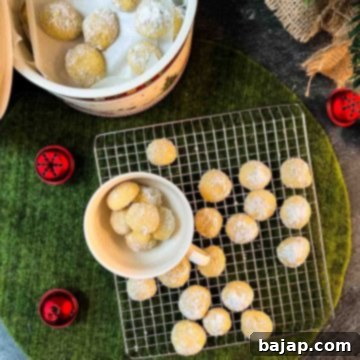Melt-in-your-mouth butterball cookies on placed on cooling rack next to tea cup filled with butterball cookies.
