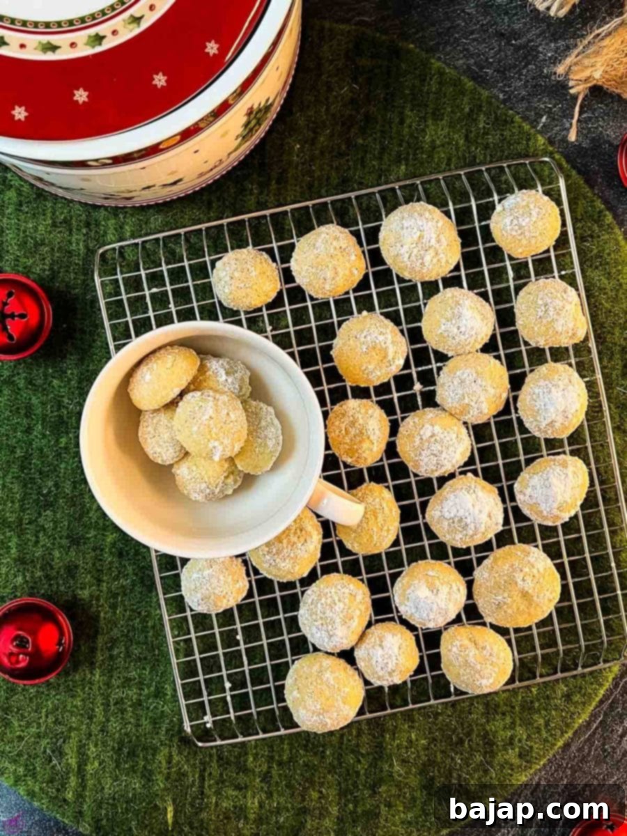 Melt-in-your-mouth butterball cookies on placed on cooling rack next to tea cup filled with butterball cookies.