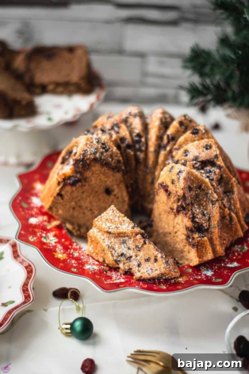 Gorgeous cranberry bundt cake with chocolate chips, cinnamon, and of course dried cranberries. Placed on a red plate.