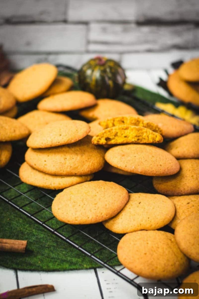 Taste Autumn's Warmth: Unbelievably Soft Pumpkin Cookies 14 Pumpkin cookies stacked on top of each other on cooling grids, with a lovely view of the soft, spiced interior.