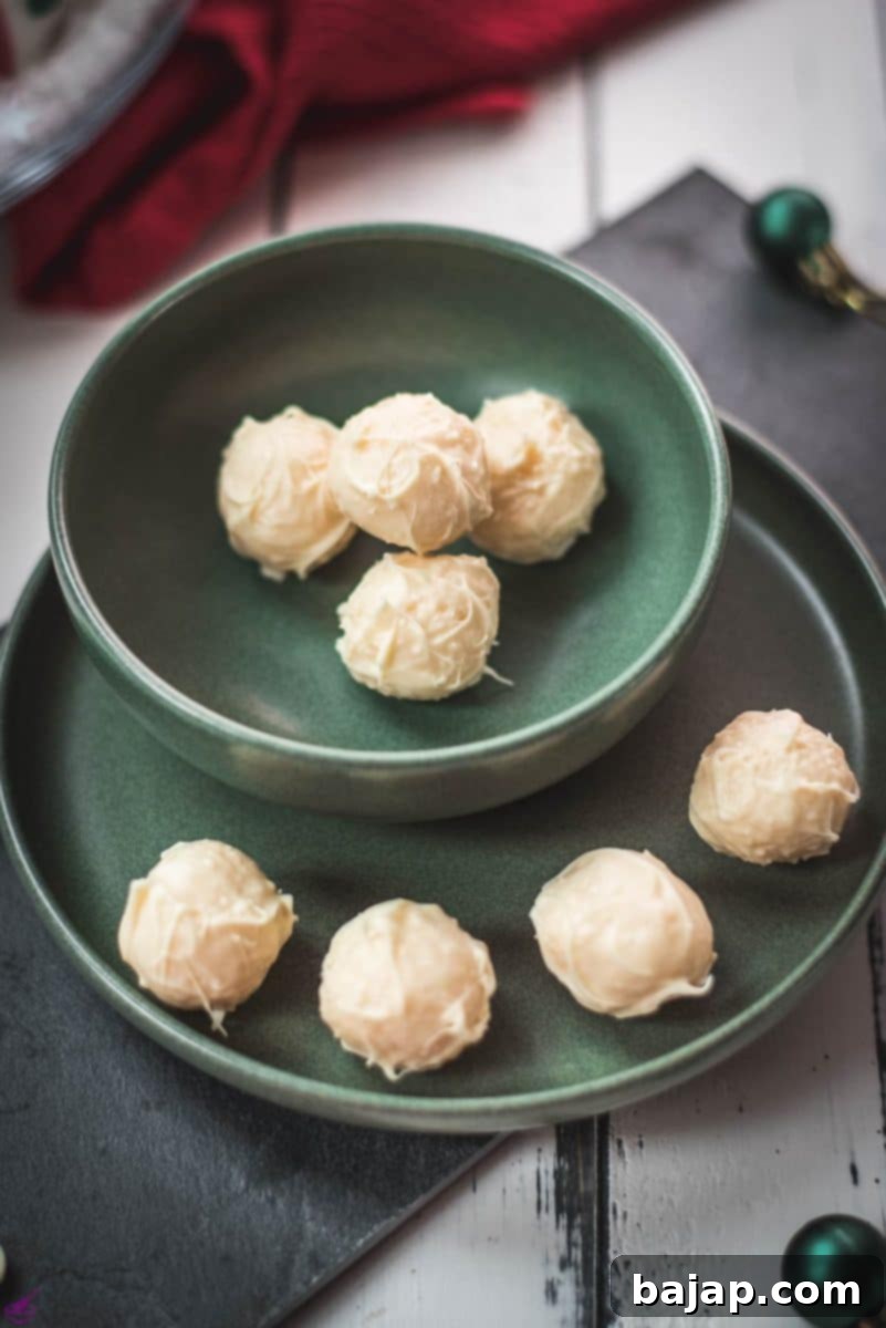 Charming coconut truffles in green bowl next to Christmas decoration.
