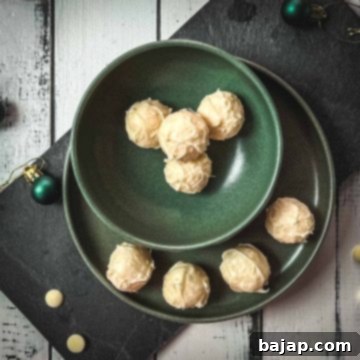 Charming coconut truffles in green bowl next to Christmas decoration.
