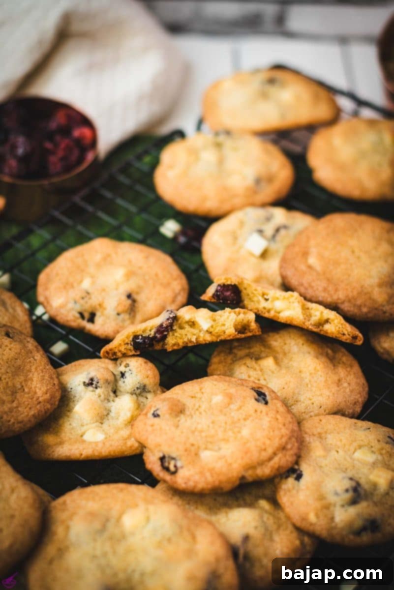 Delicious soft and chewy cranberry white chocolate chip cookies, generously packed with dried cranberries and creamy white chocolate chips, cooling on a wire rack.