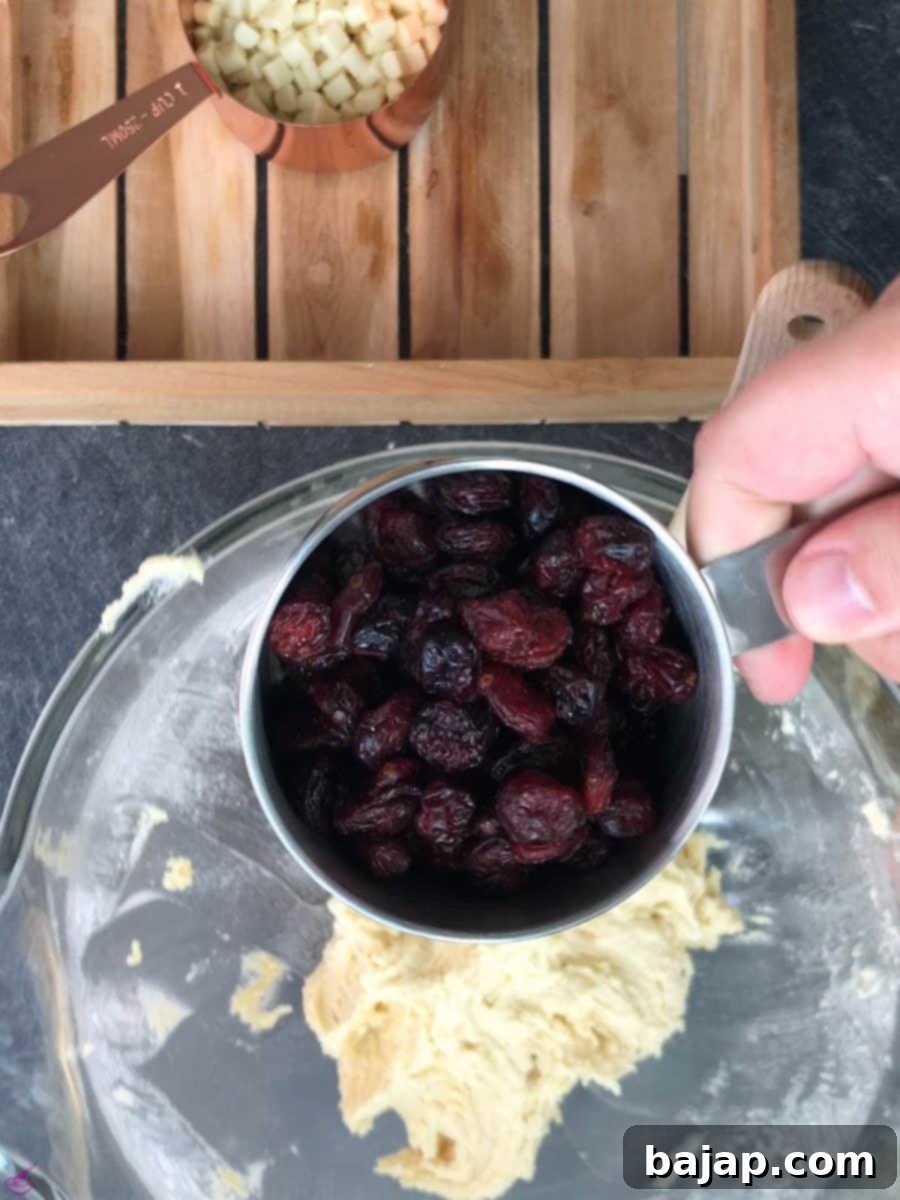 Folding in dried cranberries into the cookie dough mixture.