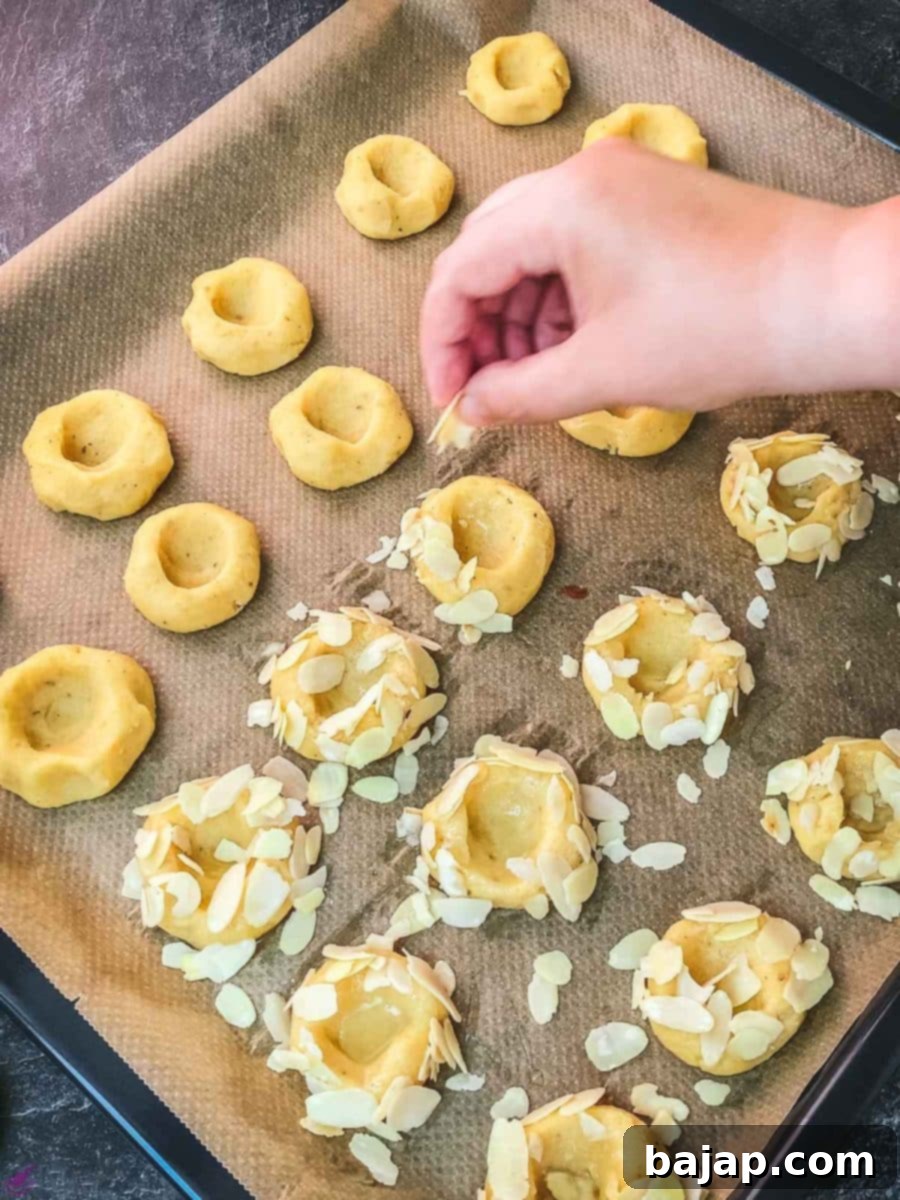Sprinkling almond slices generously over the egg-washed cookie dough balls, adding texture and flavor.