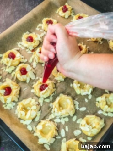 Fill the cookies indentations with raspberry jam.