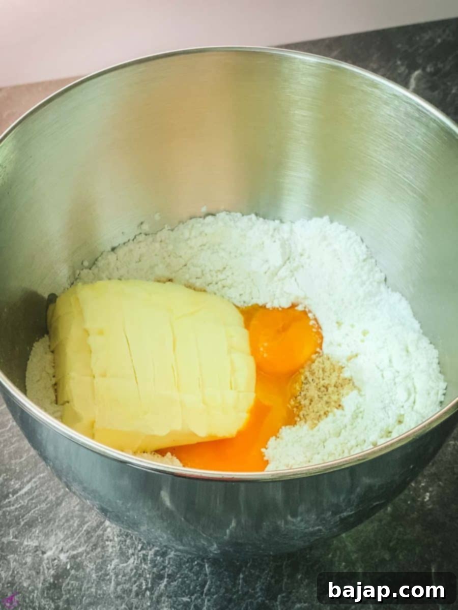 Creating a dent in the center of the sifted dry ingredients before adding powdered sugar, vanilla sugar, ground hazelnuts, egg yolks, and cubed butter.