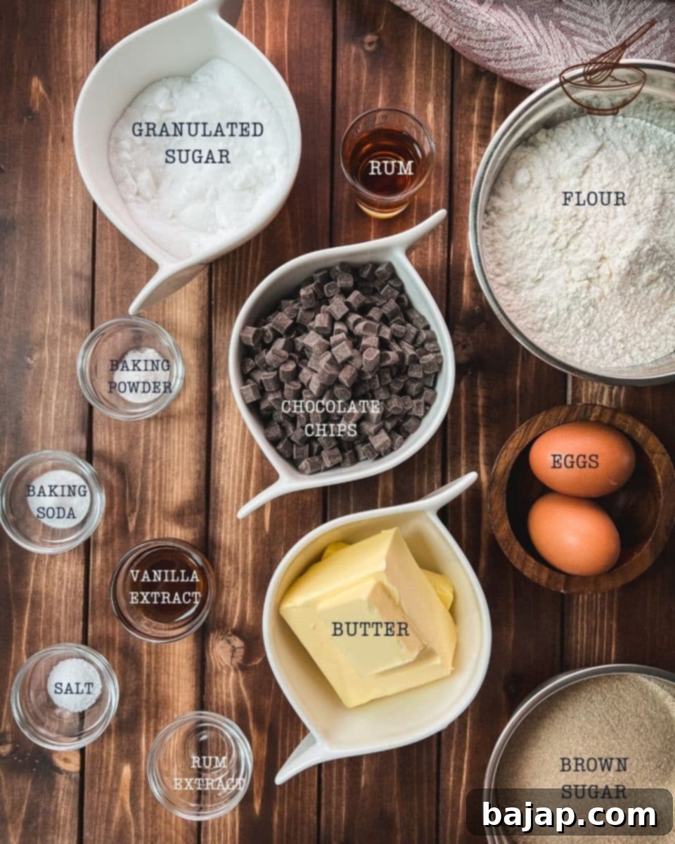 A selection of fresh, simple ingredients laid out for making delicious rum chocolate chip cookies, including butter, flour, sugars, eggs, rum, and chocolate chips.