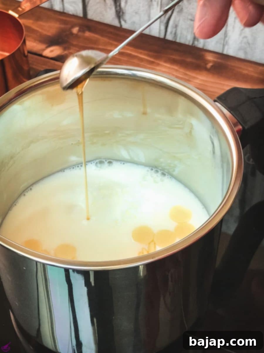 Adding vanilla extract to the milk and white chocolate chips in a saucepan.