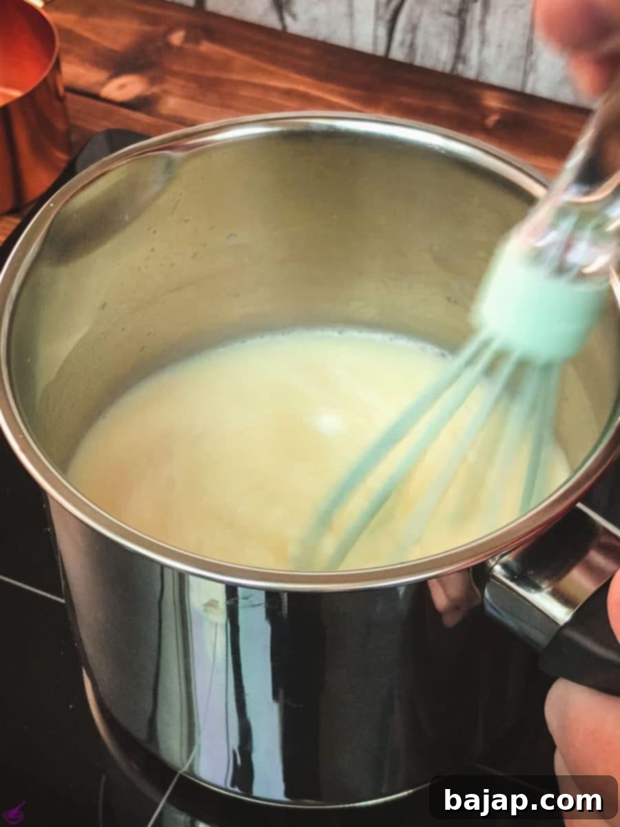 Whisking the milk and white chocolate chips in a saucepan over low heat until fully combined and smooth for the perfect hot chocolate base.