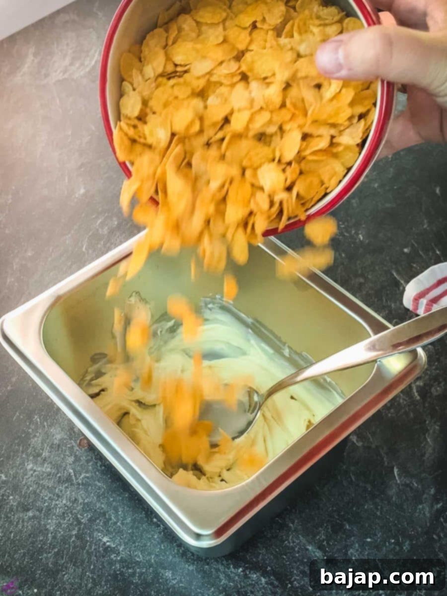 Add the cornflakes to the melted white chocolate and mix gently to coat them evenly, preserving their crispness.