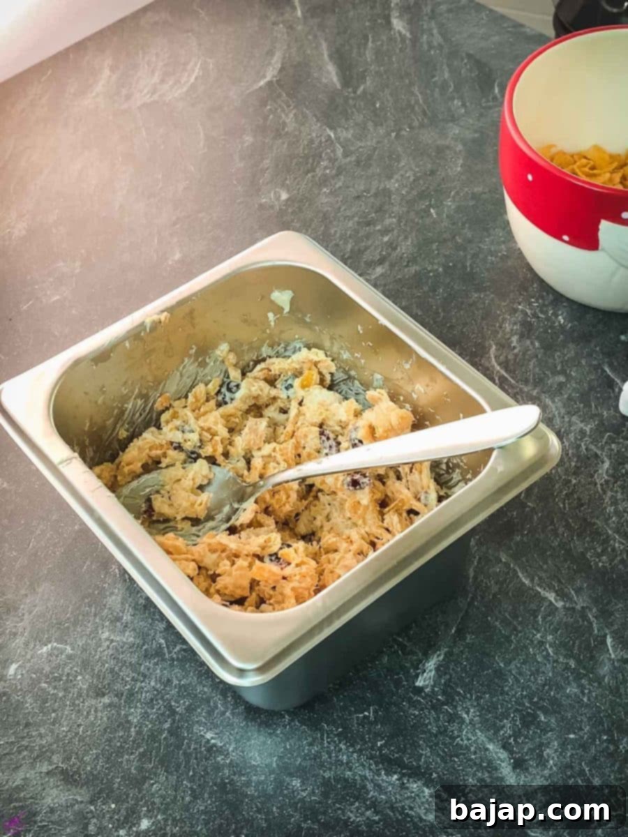 Thoroughly combine cornflakes, dried cranberries, butter, and white chocolate until all ingredients are evenly coated for perfect no-bake clusters.