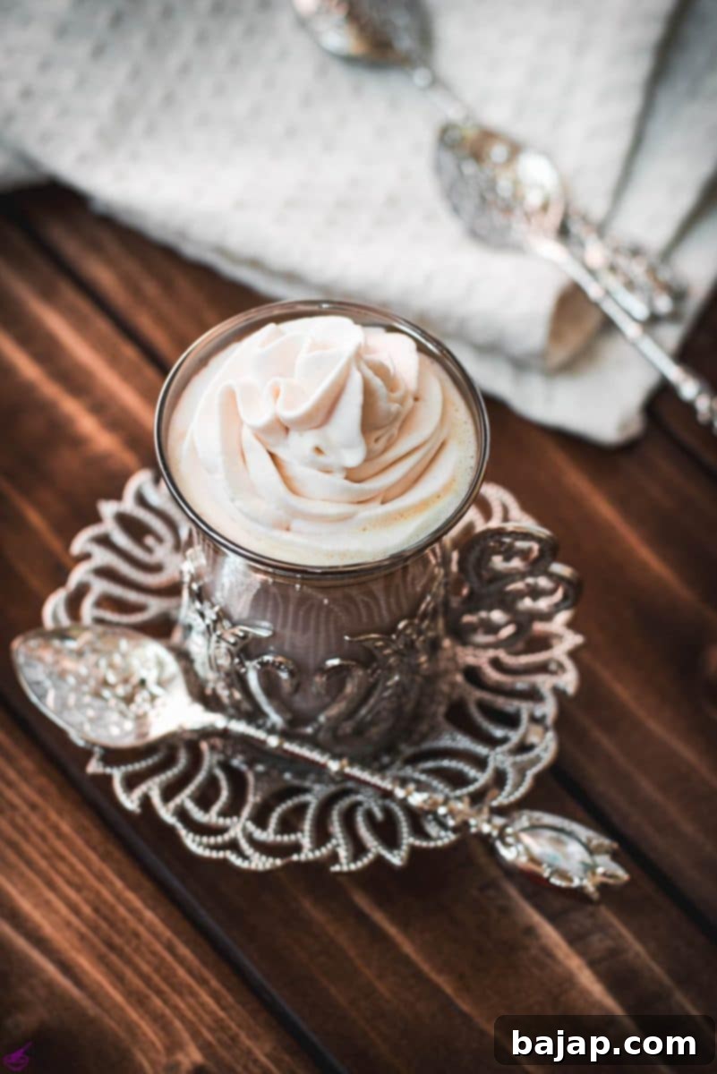 Medieval glass mug, filled with delicious strawberry white hot chocolate and topped with strawberry-flavored whipped cream.
